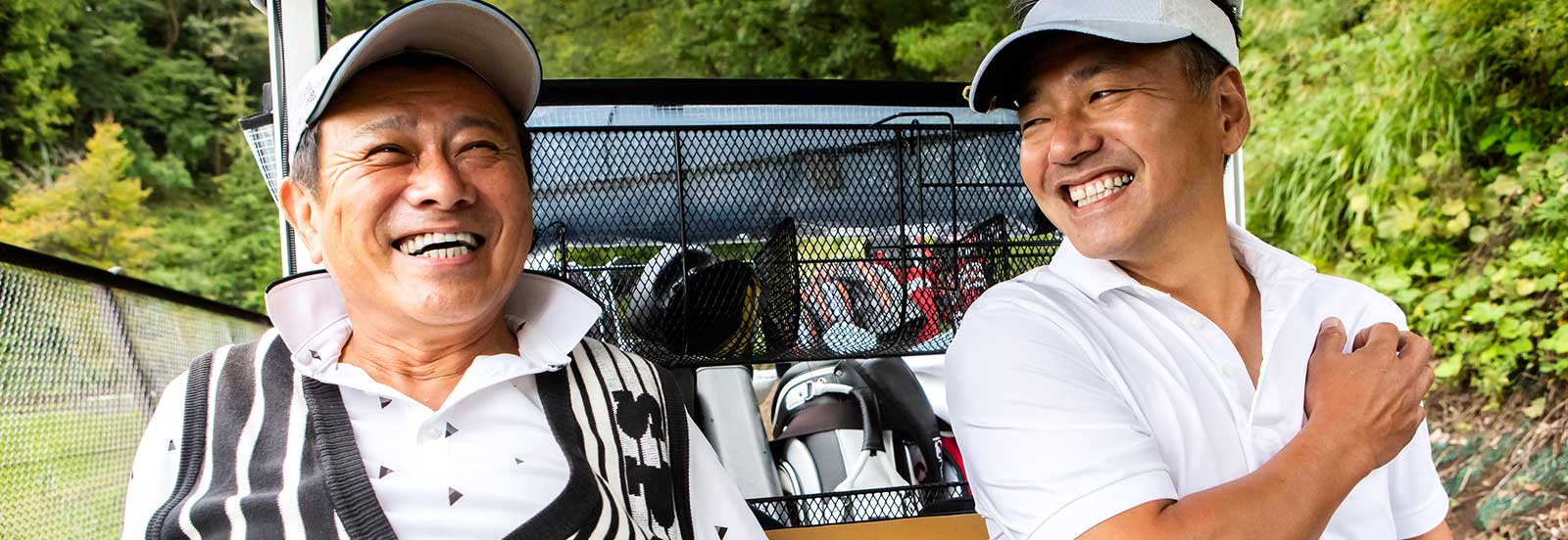 Adult father and son in a golf cart at the course. -1600x552.jpg