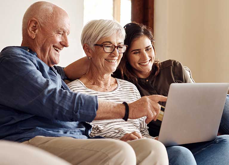 Older couple with a computer sitting next to a young lady on the couch. - 767x554.jpg